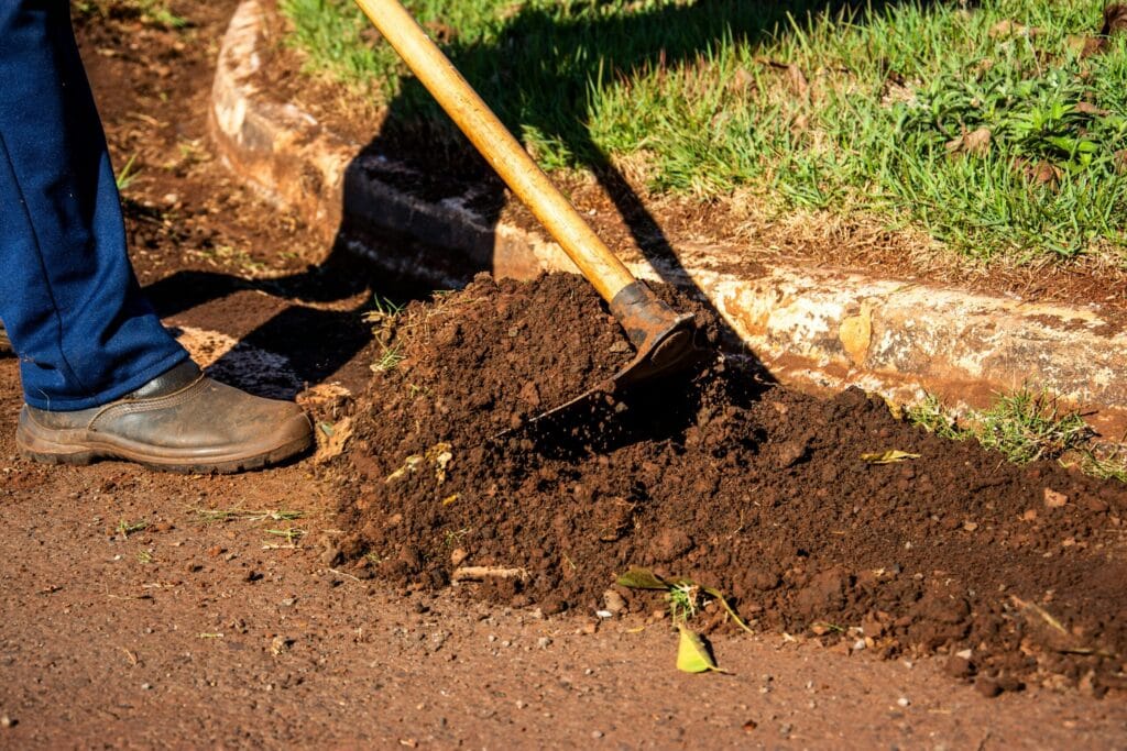 Ergonomic Garden Hoe Buying Guide (4 Types): Dig'n, Weed'n & Furrow'n Wands Close-up of gardener working soil using a hoe in Londrina, Brazil.